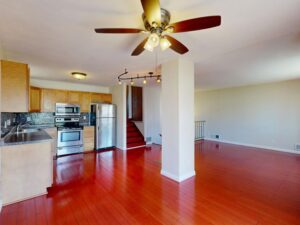 A person taking bright, clear photos of a tidy living room and kitchen in a clean, sunlit home