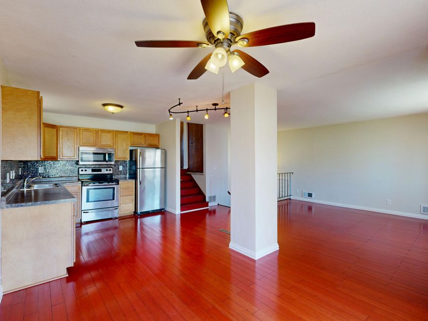 A person taking bright, clear photos of a tidy living room and kitchen in a clean, sunlit home