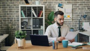 A landlord and tenant review lease documents and payment records at a kitchen table.